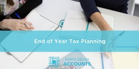 Business professionals reviewing documents together at a desk, illustrating end of year tax planning with guidance from North Devon Accounts
